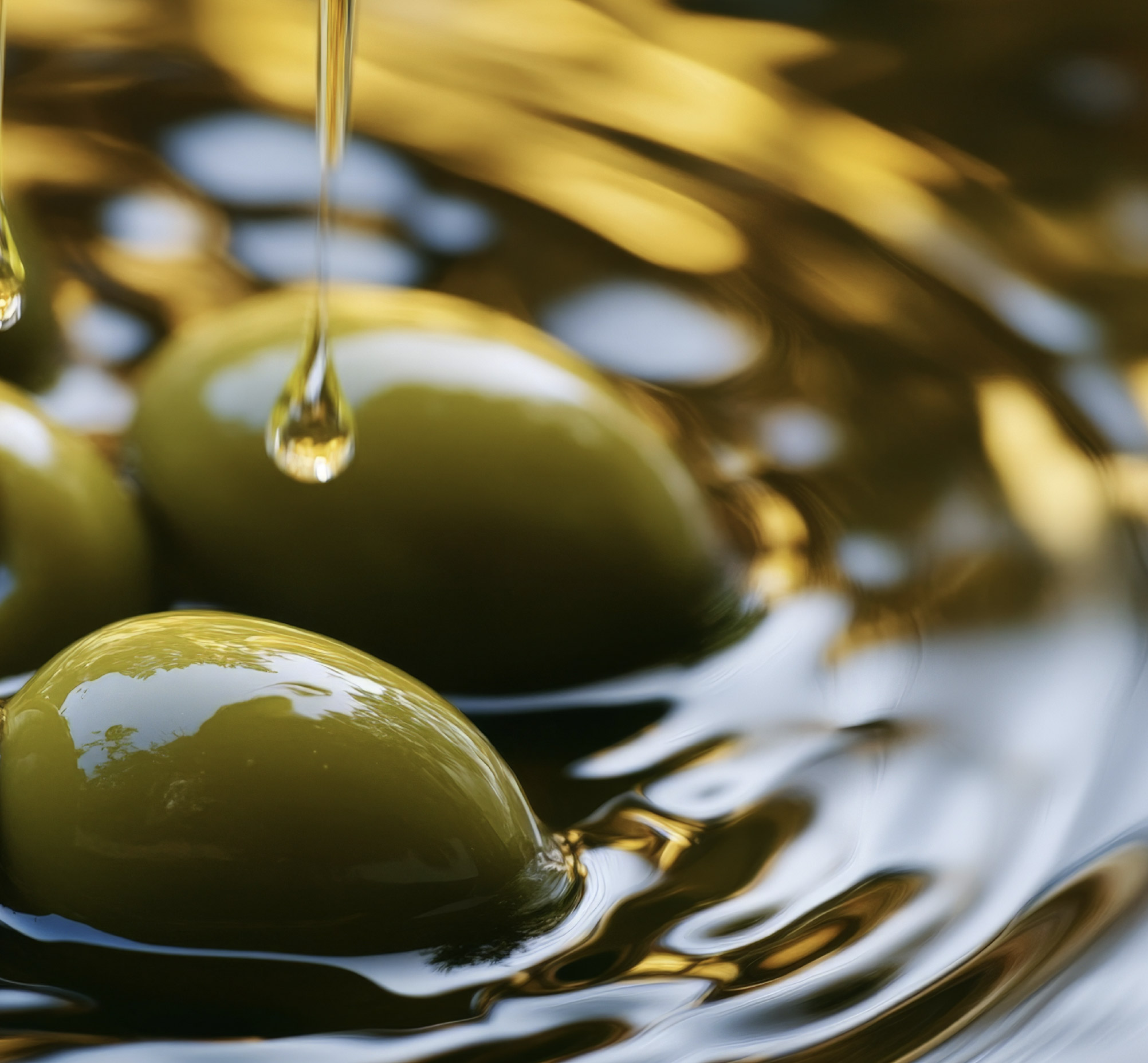 Close-up of olives immersed in golden extra virgin olive oil